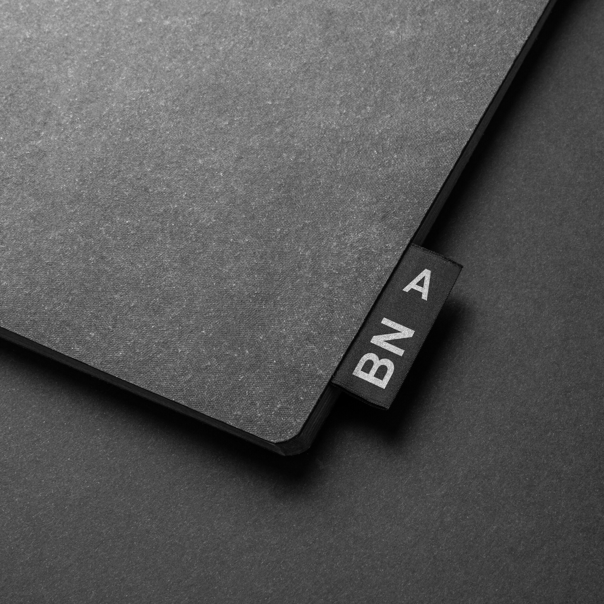 Schwarzes Mouse-Pad mit schwarzem Etikett und weissen Buchstaben