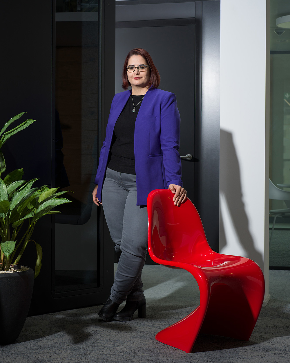 Frau mit blauem Blazer stützt sich auf roten Panton Chair ab