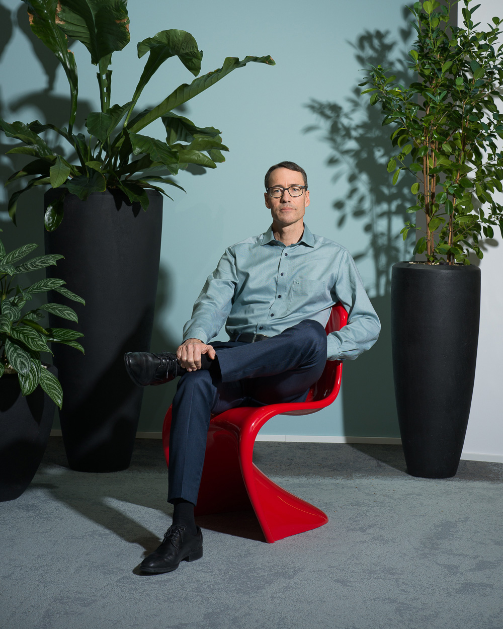Mann sitzt auf rotem Panton Chair. Pflanzen im Hintergrund